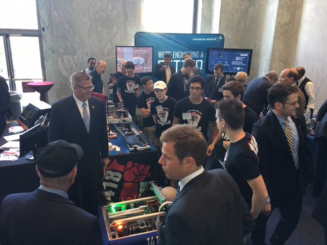 A crowd including team members and others around a table.