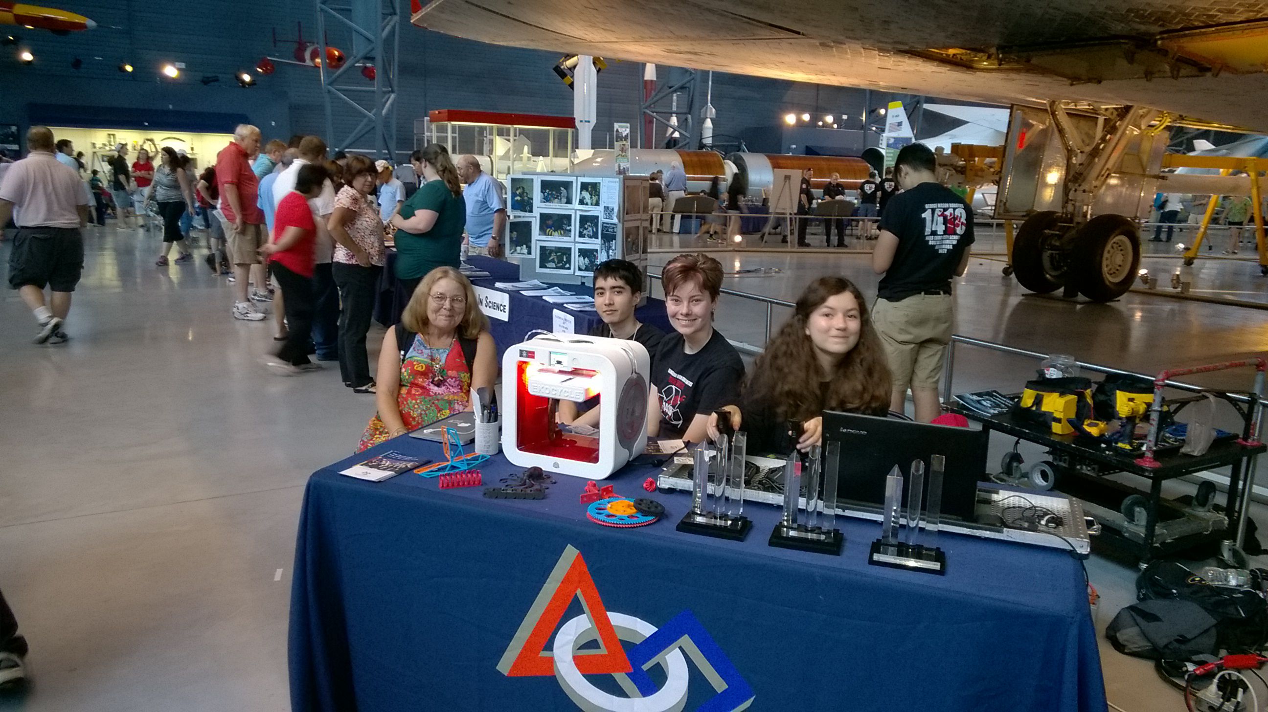 Team members sitting at a table with a 3D printer on it.