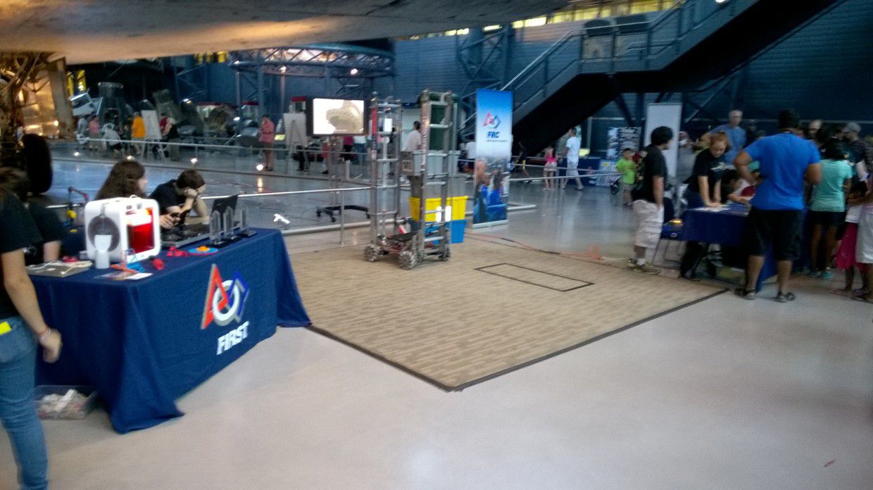 An empty room with a mat, two tables, and a robot in the middle.