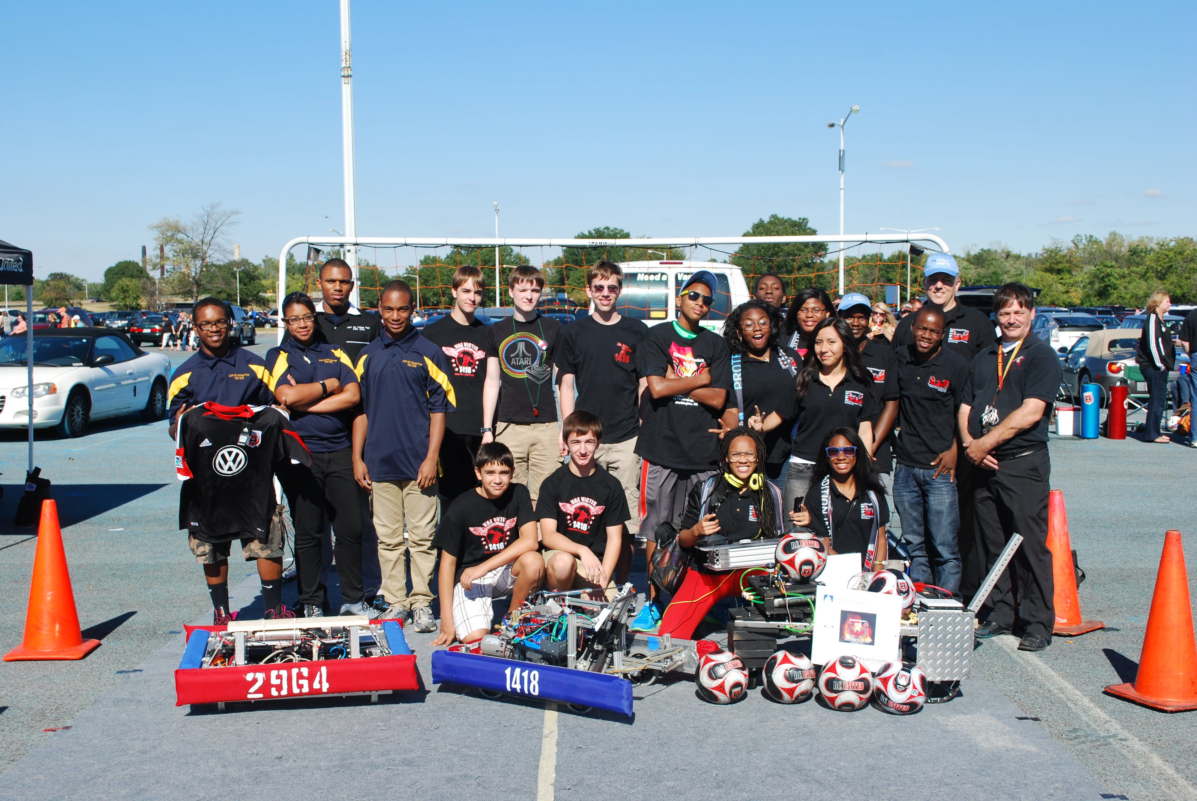 FRC Teams 2964 and 1418 posing behind their robots.